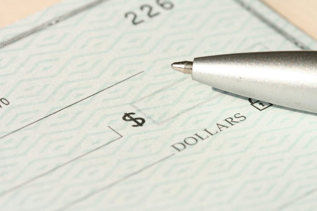 Blank payroll check and pen representing wages and employer compensation