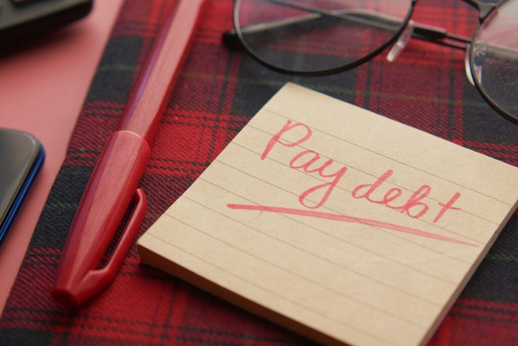Pay debt note beside a pen and glasses